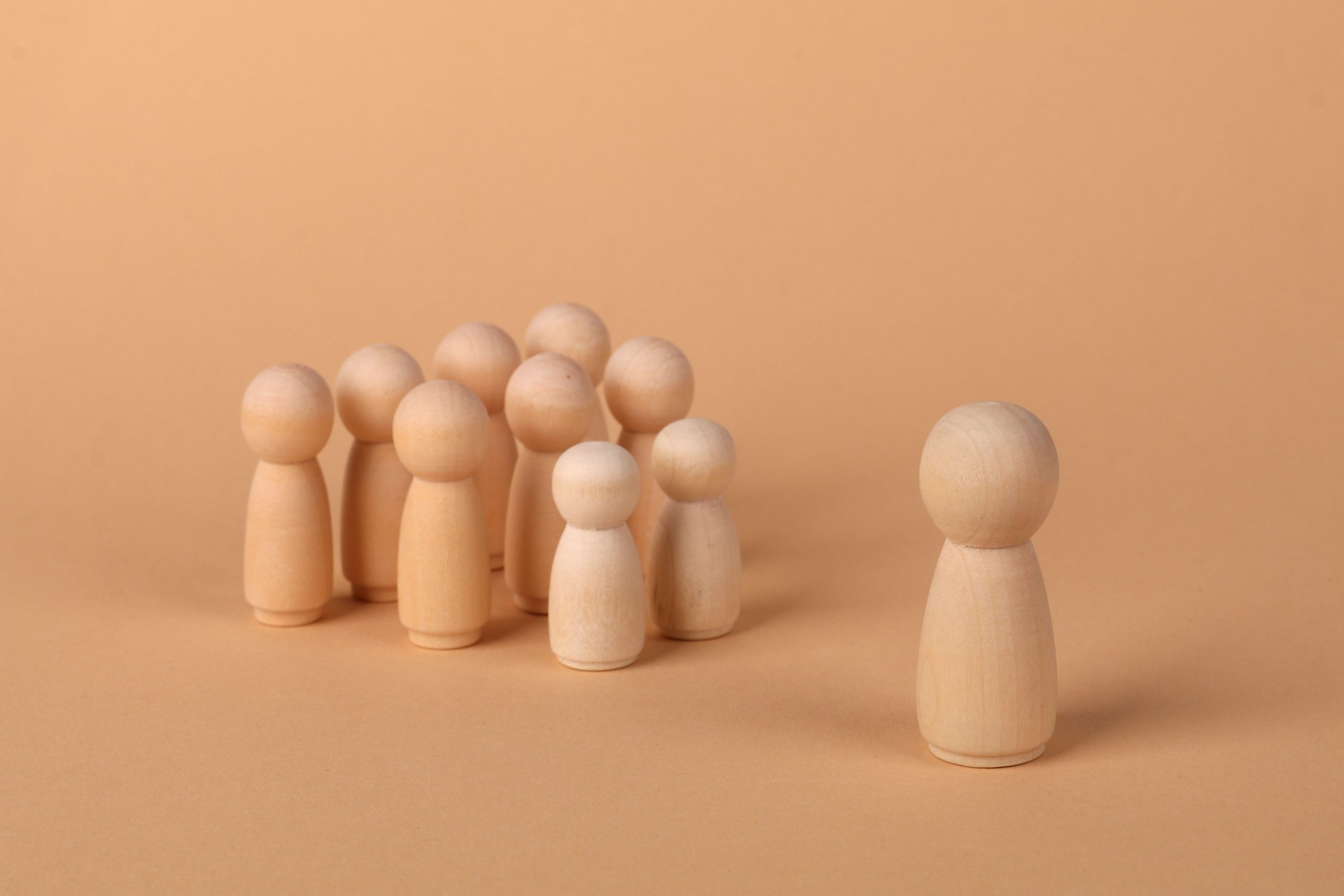 Minimalist image of wooden figures symbolizing social dynamics and isolation.